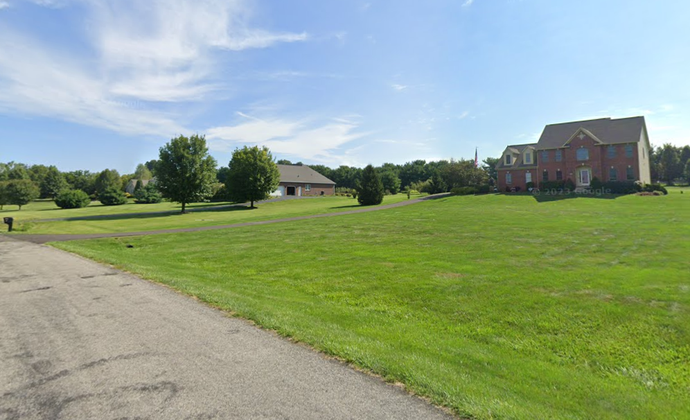 A grass field with houses and trees