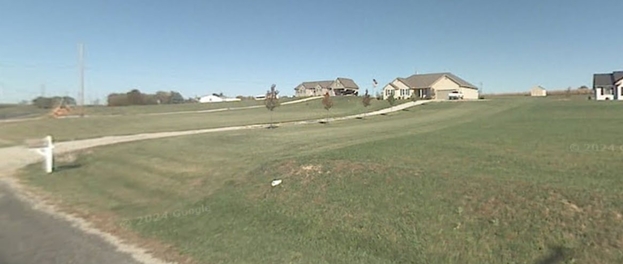 A grassy field with houses in the background
